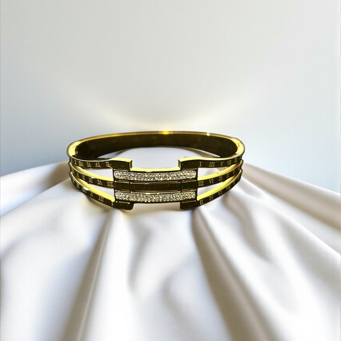 Gold bracelet with embedded stones on a white fabric background