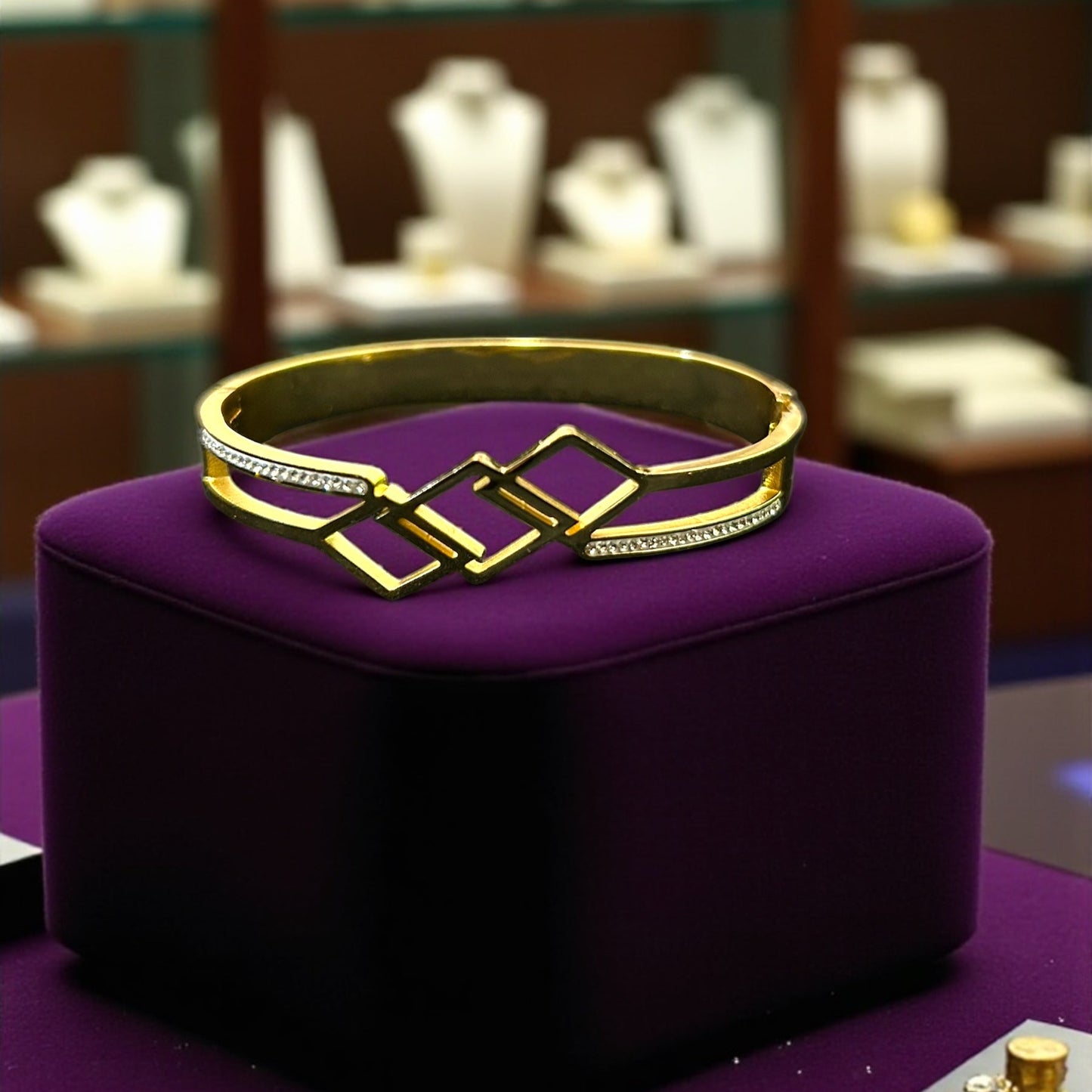Gold bracelet on a purple cushion with a jewelry store background