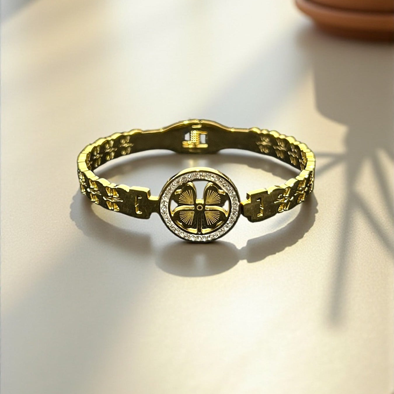 Gold bracelet with a circular design on a light surface
