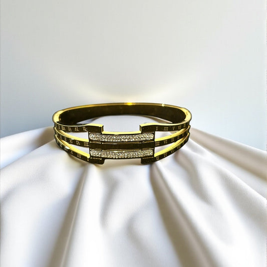 Gold bracelet with embedded stones on a white fabric background